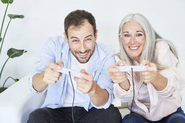 Happy mature woman with son playing video game at home - VEGF05679