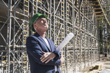 Thoughtful architect with blueprint at construction site - UUF26834