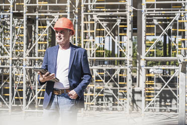 Architect with tablet PC standing at construction site - UUF26838