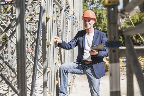 Lächelnder Ingenieur mit Tablet-PC an einem Baugerüst - UUF26840