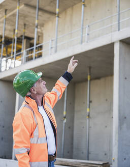 Hochrangiger Bauunternehmer mit erhobener Hand bei der Prüfung der Baustelle - UUF26846