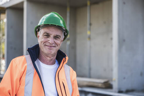 Smiling building contractor standing at construction site - UUF26849