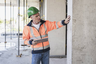 Senior contractor with tablet PC examining column - UUF26851