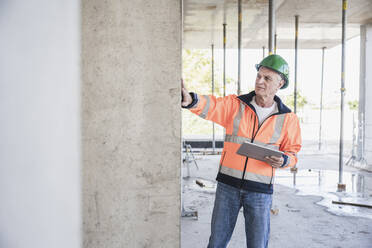 Senior contractor holding tablet PC examining column - UUF26852