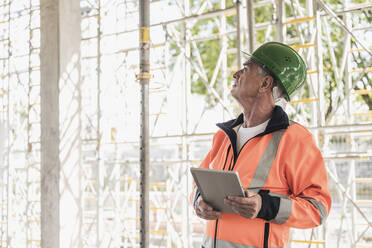 Hochrangiger Bauunternehmer mit Tablet-PC bei der Untersuchung einer Baustelle - UUF26856