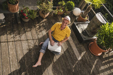 Glücklicher Mann mit Laptop auf der Terrasse sitzend - UUF26874
