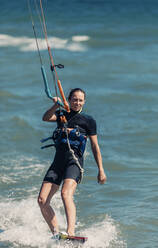 Lächelnde Frau beim Kiteboarden im Meer - DMGF00805