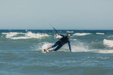 Mature man kiteboarding in sea on sunny day - DMGF00807