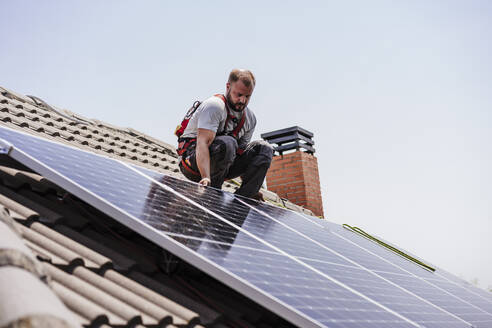 Techniker bei der Installation von Sonnenkollektoren auf dem Dach - EBBF05675