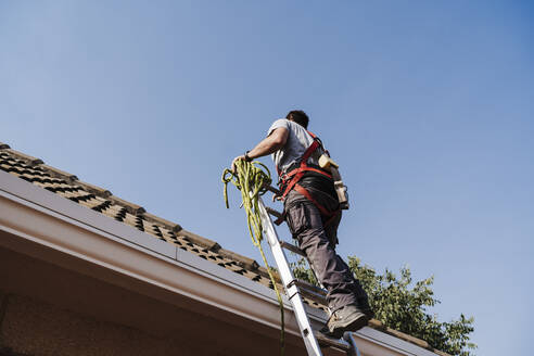 Techniker steigt auf einer Leiter auf dem Hausdach auf - EBBF05677