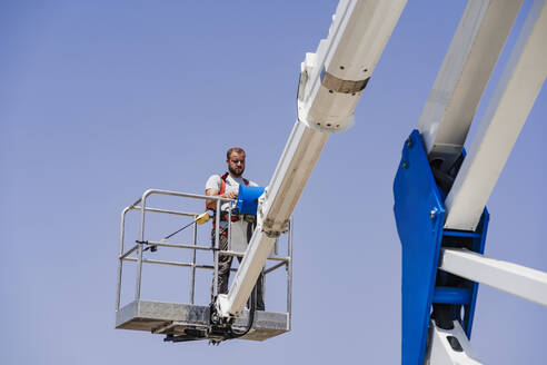 Electrician operating hydraulic platform on sunny day - EBBF05685