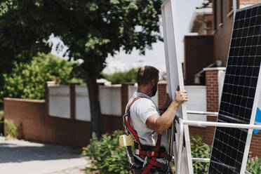 Handwerker lädt an einem sonnigen Tag ein Solarmodul in eine Hebebühne - EBBF05692