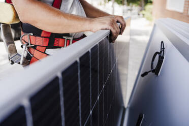 Nahaufnahme eines Elektrikers, der ein Solarpanel hält - EBBF05698