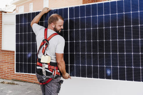 Techniker trägt schweres Solarpanel - EBBF05699