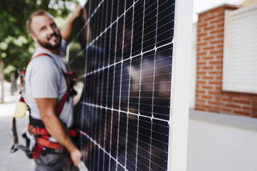 Handwerker trägt schweres Solarpanel - EBBF05701