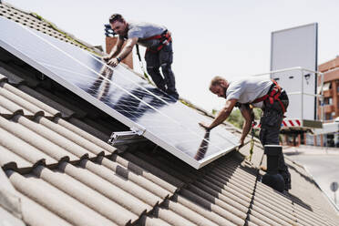 Techniker bei der Installation von Solarzellen auf dem Dach - EBBF05703
