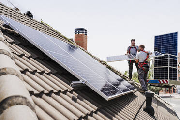 Elektriker bei der Installation von Solarzellen auf dem Dach - EBBF05704