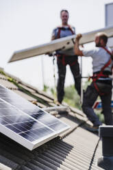 Elektriker bei der Installation von Solarzellen auf dem Hausdach - EBBF05706