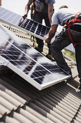 Mitarbeiter eines Elektrikers bei der Installation von Solarzellen auf dem Dach - EBBF05707