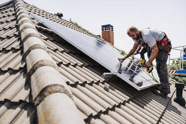 Elektriker bei der Installation von Solarzellen auf dem Hausdach - EBBF05708