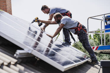 Handwerker installieren Sonnenkollektoren auf dem Dach eines Hauses - EBBF05709