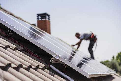 Elektriker bei der Installation von Sonnenkollektoren auf dem Dach - EBBF05715