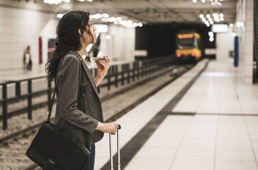 Transgender businesswoman wearing blazer talking on phone standing at subway station - UUF26888