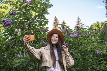 Lächelnde Frau, die im Park ein Selfie mit ihrem Handy macht - VPIF06702