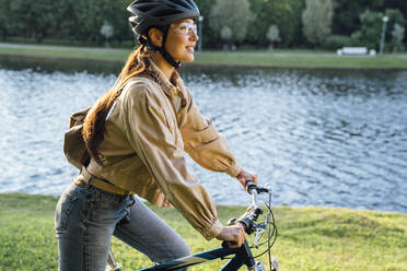 Frau fährt Fahrrad am See im Park - VPIF06722