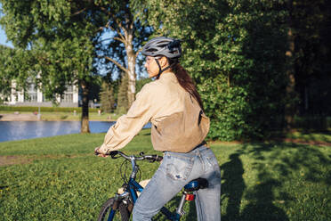 Frau fährt Fahrrad im Park an einem sonnigen Tag - VPIF06724