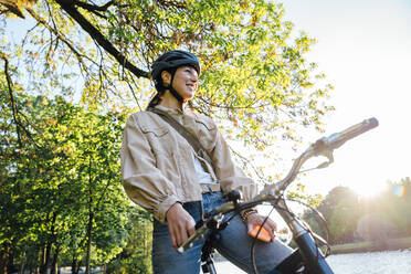 Lächelnde Frau mit Smartphone auf dem Fahrrad sitzend im Park - VPIF06728