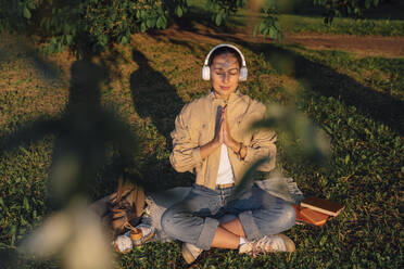 Woman with eyes closed meditating in park on sunny day - VPIF06741