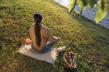 Woman meditating on grass at park - VPIF06747