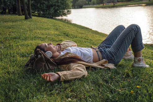 Frau liegt im Gras am See im Park - VPIF06765