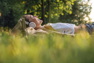 Smiling woman lying on grass at park - VPIF06766
