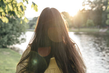 Frau mit langen Haaren schaut auf einen See im Park - VPIF06777