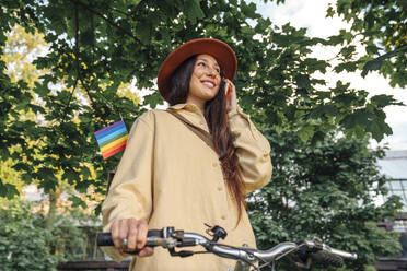 Happy woman talking on mobile phone with bicycle at park - VPIF06783
