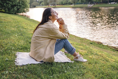 Frau sitzt am See im Park - VPIF06791