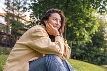 Happy woman sitting at park - VPIF06793