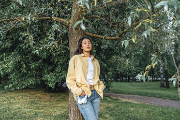 Woman relaxing standing in front of tree - VPIF06799