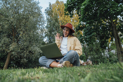 Lächelnde Frau, die über einen Laptop im Park ein Videogespräch führt - VPIF06809