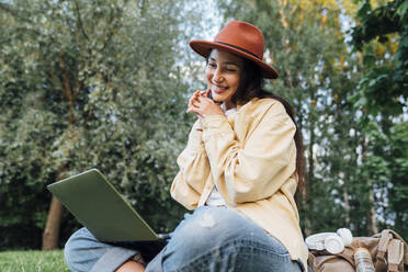 Lächelnde Frau bei Videoanruf über Laptop im Park - VPIF06811