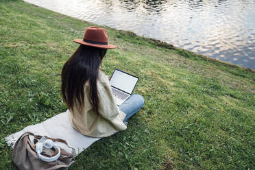 Freiberufler arbeitet am Laptop vor einem See im Park - VPIF06813