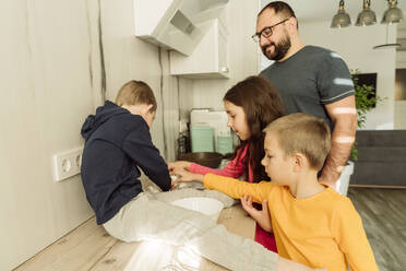 Lächelnder Vater mit Kindern bei der Zubereitung des Frühstücks in der Küche - OSF00391