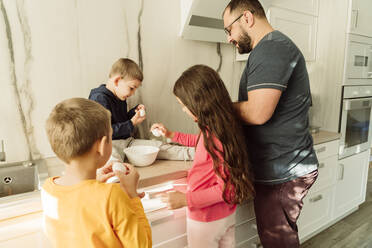Mann mit Kindern bereitet Frühstück in der Küche vor - OSF00393