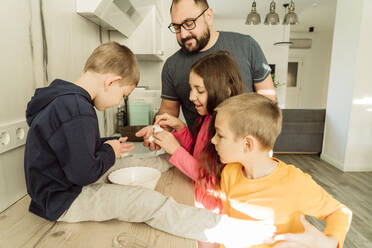 Kinder schenken dem Vater in der Küche Eierschalen - OSF00395