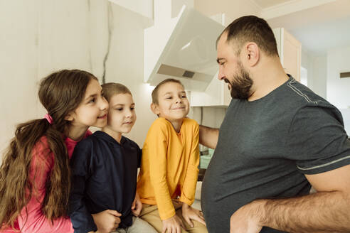 Lächelnder Vater im Gespräch mit Kindern in der Küche - OSF00399