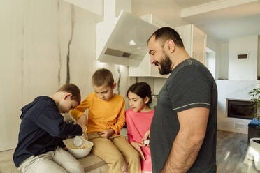 Glücklicher Vater, der seinen Kindern bei der Zubereitung eines Omeletts zu Hause hilft - OSF00400