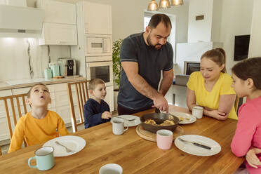 Vater serviert Frau und Kindern zu Hause das Frühstück - OSF00410