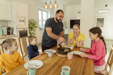 Lächelnder Vater serviert der Familie zu Hause das Frühstück - OSF00411